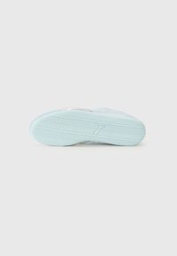 Sneaker sole with a light blue rubber material. Features a textured surface with a herringbone pattern and a subtle logo near the heel.
