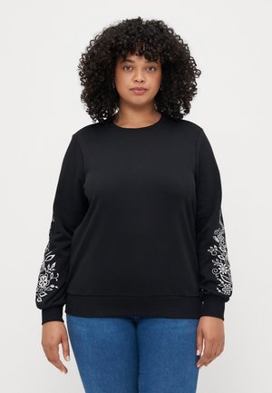 Black sweatshirt made of soft fabric, featuring white floral embroidery on the sleeves and a ribbed neckline and cuffs. Casual fit.