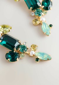 Goldfarbene Ohrringe mit großen Smaragd- und Teal-Steinen, kleinen grünen und gelben Edelsteinen sowie einem Perlenakzent, angeordnet in einem blumigen Design.