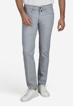 Light gray, slim-fit jeans with a smooth texture, standard pockets, and a single button closure. Paired with white sneakers.