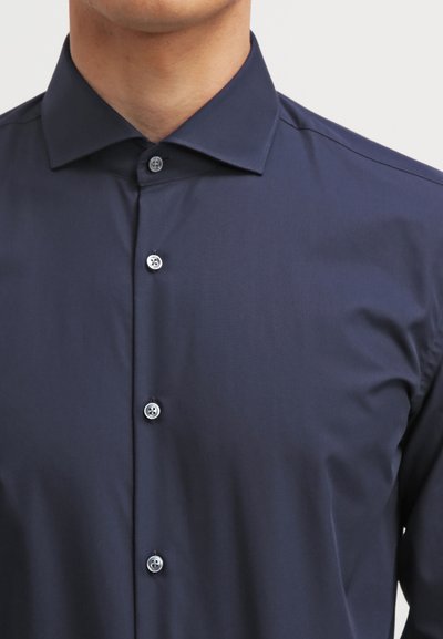 Chemise bleu marine à manches longues en tissu lisse, dotée d'un col classique et de cinq boutons blancs sur le devant.