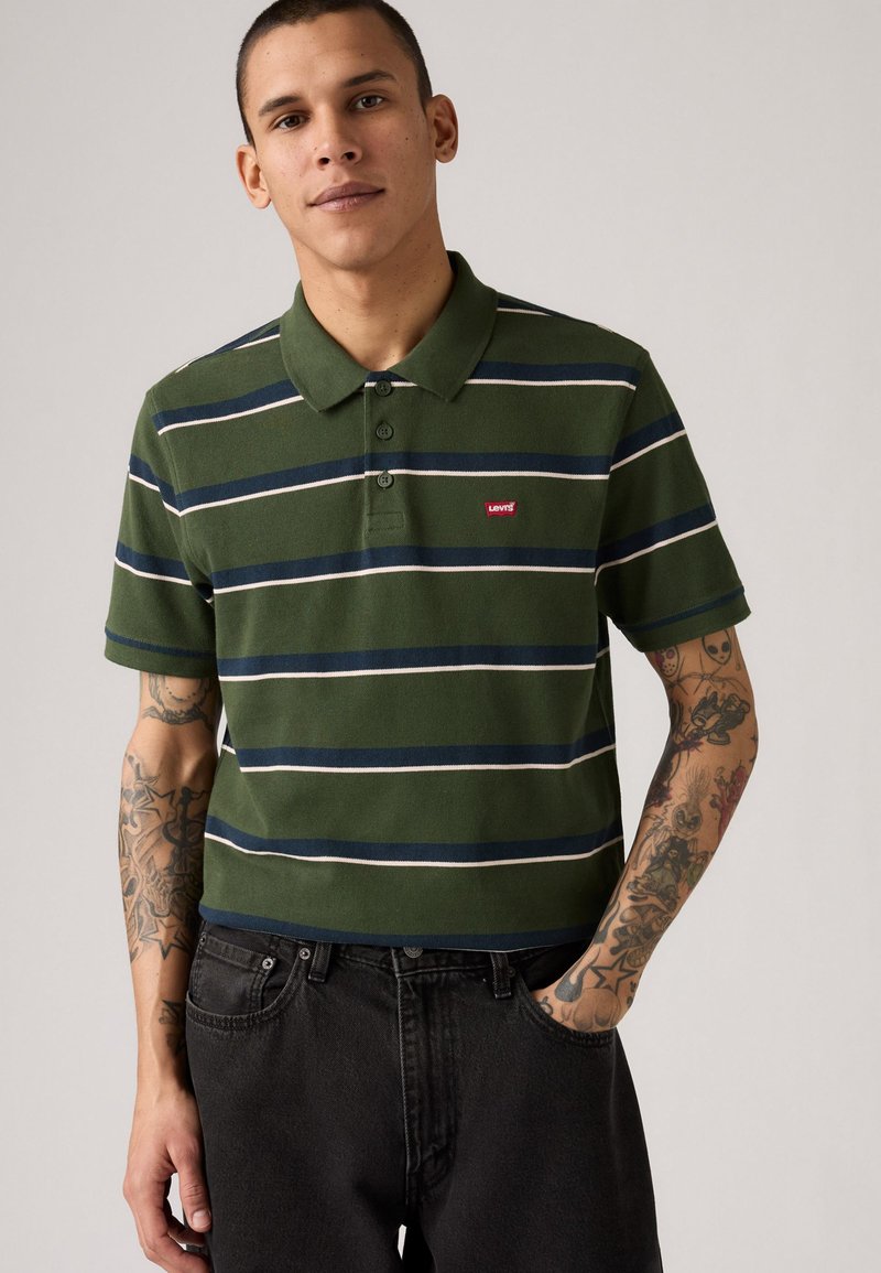 Zelený pruhovaný polokošeľ s námorníckymi a bielymi horizontálnymi pruhmi. Obsahuje golier, zapínanie na tri gombíky a malé červené logo Levi's.