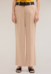 Beżowe spodnie o szerokich nogawkach z pionowymi paskami, z teksturowanym czarnym paskiem z dużą okrągłą klamrą. Gładka tkanina z luźnym krojem.