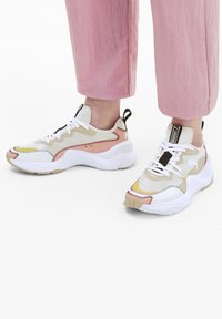 Puma-sneakers med en vit, beige och rosa färgsättning, strukturerad ovandel, kontrasterande sömmar och en tjock sula med gummigrepp.