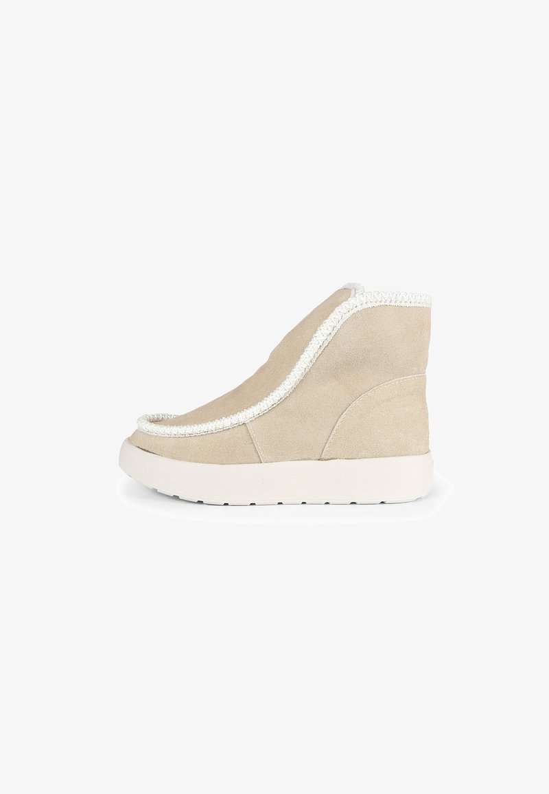 Botín de ante beige con costuras blancas, diseño de punta redonda y suela texturizada. Altura media, acabado suave y forma aerodinámica.