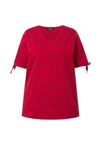 T-shirt en coton rouge avec col en V, manches courtes et détails à nouer aux poignets. Présente des motifs de papillons noirs sur l'ensemble.