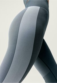 Legginsy o wysokim stanie z teksturowanej ciemnoszarej tkaniny z jasnoszarymi paskami, uformowane w dopasowaną sylwetkę.