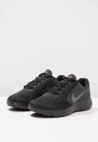 Scarpe da ginnastica nere con una scocca in rete e materiale sintetico, superficie texturizzata e punta rotonda. Presentano un logo scuro e un design con lacci.