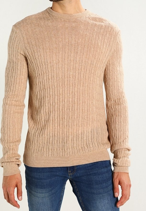 Ljusbeige stickad tröja med ribbad struktur, rund halsringning och långa ärmar. Har åtsittande muddar och fåll. Matchas med blå jeans.