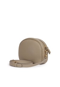 Borsa a tracolla rotonda in morbida pelle beige con una finitura testurizzata, accessori in tonalità oro e una sottile tracolla regolabile. Dettagli con chiusura a zip.