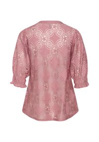 Blouse rose avec un motif de dentelle florale, un col rond et des manches bouffantes. Tissu texturé avec un léger éclat et des poignets élastiqués.