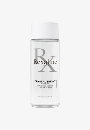 Klare Glasflasche mit einem weißen Deckel. Das Etikett zeigt "Rexaline Labs" und "Crystal Bright Lotion" in schwarzem Text. Enthält Hyaluronsäure.
