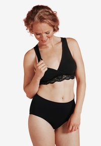 Svart trådlös bralette med djup V-ringning och spetskant, ihopparad med högmidjade svarta trosor. Mjuk, stretchig tyg med len textur.