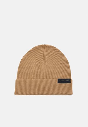 Bonnet en maille côtelée marron clair avec revers plié et petite étiquette noire portant l'inscription "Tommy Hilfiger" sur le devant du revers.