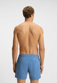 Blåmönstrade badshorts med elastisk midja och sidofickor, med ett diagonalt vågmönster i ett texturerat tyg.