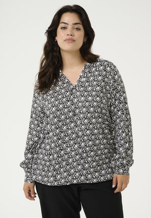 Svartvit mönstrad blus med långa ärmar och V-ringning, med en abstrakt design på lätt tyg.