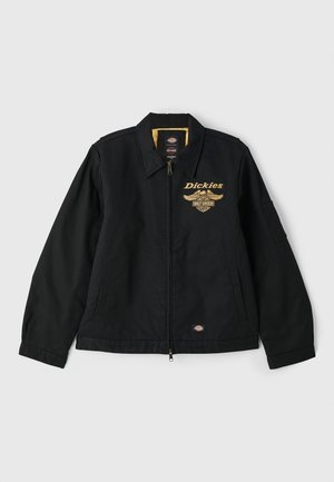 Zwarte jas met een ritssluiting aan de voorkant, grote kraag, gele voering en geborduurd "Dickies" logo met vleugels. Voorzien van zijzakken en lange mouwen.