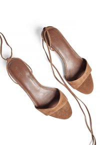 Brown suede heeled sandals with open toes, soft straps for ankle support, and a smooth leather insole. Minimalist design with a flat sole.