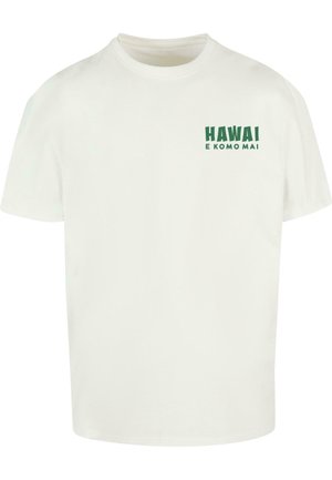 T-shirt en coton blanc avec le texte vert "HAWAI E KOMO MAI" sur la poitrine gauche. Manches courtes, design col rond, coupe décontractée.