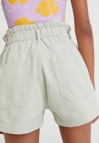 Světle zelené, vysoké šortky s elastickým pasem, které mají dvě zadní kapsy a strukturovanou bavlněnou tkaninu.