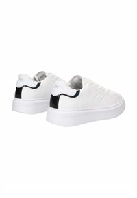 Sneakers bianchi con tomaia in pelle liscia, dettagli nero testurizzati sul tallone, suola in gomma bianca piatta e design minimalista con lacci.