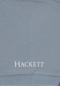 Světle modrý pletený svetr s žebrovanými manžetami a lemem, s bílým vyšitým logem "HACKETT" na hrudi.