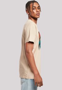 Beige katoenen t-shirt met korte mouwen, voorzien van een kleurrijk grafisch ontwerp op de voorkant. De pasvorm is relaxed, met een rechte zoom.