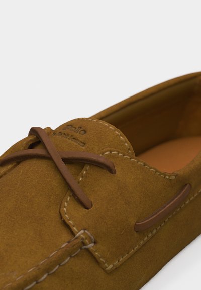 Καφέ δερμάτινο μοκασίνι από σουέτ με δερμάτινα κορδόνια και εμφανείς ραφές, με το λογότυπο "Polo Ralph Lauren" στο μπροστινό πάνω μέρος.