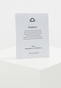 Eine weiße Karte mit abgerundeten Ecken enthält Text über das Sternzeichen Waage, einschließlich Symbol, Daten und dem Markennamen "PILGRIM" in schwarzer Schrift.