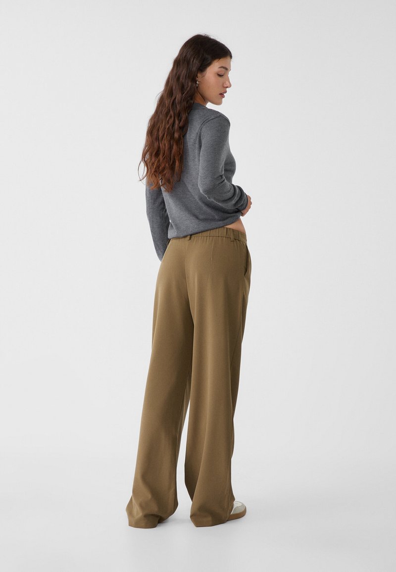 Haut gris à manches longues et pantalon large en kaki à coupe décontractée, doté d'une texture lisse et d'une taille élastique. Design simple avec des couleurs neutres.