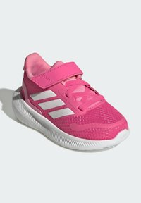 Scarpa sportiva rosa con tomaia in rete, dettagli bianchi e chiusura con strap in Velcro. Punta arrotondata e suola testurizzata per aderenza e flessibilità.
