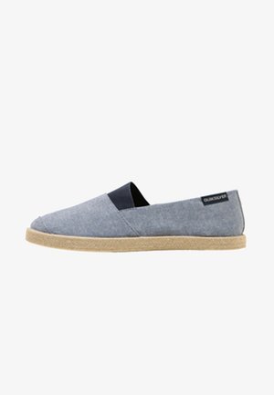 Blue canvas slip-on shoe with a textured light gray upper, contrasting navy elastic side accents, and a beige woven jute sole.