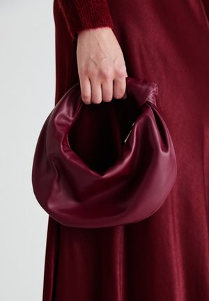 Borsa in pelle bordeaux con un design morbido e arricciato e una forma arrotondata. Il manico è fissato, mostrando una texture liscia.