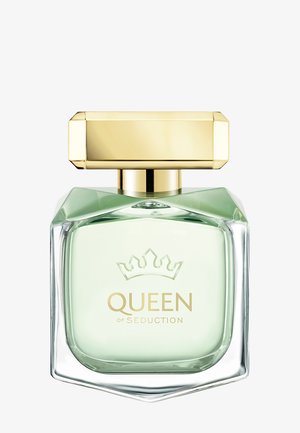 Flacon de parfum en verre carré avec liquide vert pâle, logo couronne doré et bouchon rectangulaire doré, étiqueté "QUEEN OF SEDUCTION."