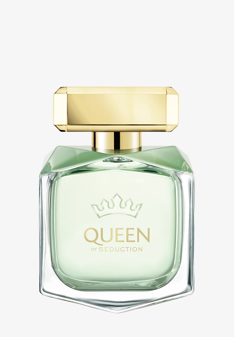 Flacon de parfum en verre carré avec liquide vert pâle, logo couronne doré et bouchon rectangulaire doré, étiqueté "QUEEN OF SEDUCTION."