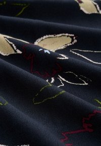 Mornarska tkanina s cvjetnim uzorkom koja sadrži svijetlosmeđe cvjetove i crvene akcente. Mekana tekstura s vidljivim nabora i konturama materijala.