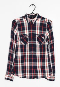 Lange mouw geruite overhemd in marineblauw, rood en grijs. Heeft een knoopsluiting aan de voorkant, twee borstzakken en een gebogen onderrand. Gemaakt van zachte stof.