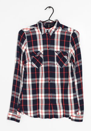 Lange mouw geruite overhemd in marineblauw, rood en grijs. Heeft een knoopsluiting aan de voorkant, twee borstzakken en een gebogen onderrand. Gemaakt van zachte stof.