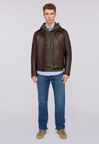 Brun läderjacka, grön hoodie, ljusblå skjorta, blå jeans och beige sneakers. Slät textur, åtsittande design, dragkedjefickor.