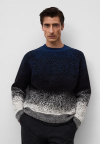 Sweter w niebiesko-czarnym gradiencie o puszystej fakturze, z okrągłym dekoltem i ściągaczami. Dolna część przechodzi w szary i biały kolor.