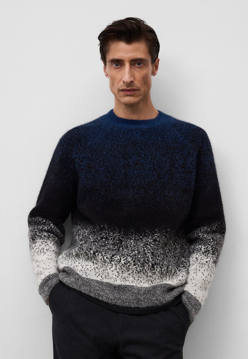 Sweter w niebiesko-czarnym gradiencie o puszystej fakturze, z okrągłym dekoltem i ściągaczami. Dolna część przechodzi w szary i biały kolor.