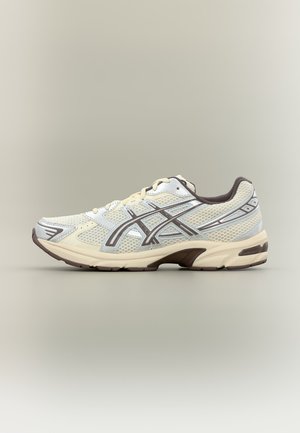 Lys beige og brun mesh løpesko med hvite og brune detaljer, lav modell, vist på nøytral bakgrunn.