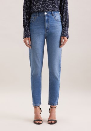 Jean taille haute bleu clair avec une coupe slim et longueur cheville, présentant une texture lisse et un design classique à cinq poches.