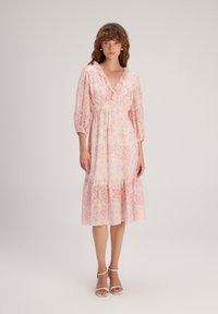 Robe à motif floral rose avec un décolleté en V, des manches bouffantes et un ourlet à volants superposés. Fabriquée en matière légère, elle présente une taille élastique.