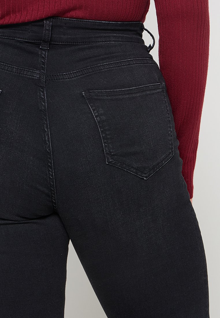 Hoch geschnittene schwarze Jeans mit einer glatten Textur, die mit einem klassischen Fünf-Taschen-Design und dezenten Nähdetails ausgestattet sind.