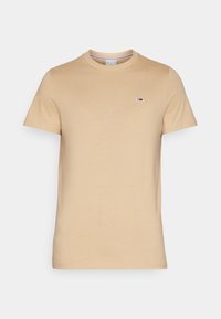 Bežové bavlněné tričko s kulatým výstřihem a krátkými rukávy. Na levé části hrudi se nachází malé logo. Hladká textura, standardní střih.