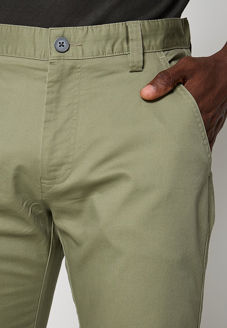 Khaki katoen broek met een rechte snit, voorzakken en een knoopsluiting met zichtbare stikdetails. De textuur is glad.