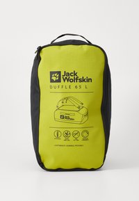 Gele sporttas met zwarte accenten, gelabeld "Jack Wolfskin DUFFLE 65 L." Kenmerken zijn een rits, handgrepen en iconen voor waterafstotendheid en recycleerbaarheid.