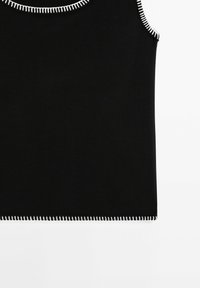 Haut en maille noir sans manches avec des surpiqûres blanches contrastantes le long de l'encolure, des emmanchures et de l'ourlet.