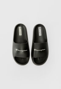 Svarte sandaler i matte syntetisk materiale. Har en bred stropp med "Champion"-logo i hvitt. Åpen tå-design.